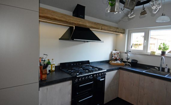 Moderne keuken met los fornuis, waarbij de afzuigkap verwerkt is in een massief eiken balk.